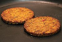 Two Morningstar Farms Tomato & Basil Pizza veggie burgers on a frying pan