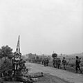 Infantry moving up past a knocked-out German 88mm gun