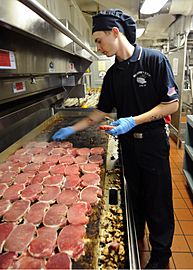 US Navy 100821-N-2686K-030 Culinary Specialist Seaman Cody D. Cunningham prepares pork chops for lunch in the galley aboard USS George H.W. Bush (CVN 77)