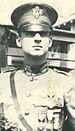 Head and shoulders of an officer in a neatly pressed military uniform with medals hanging from ribbons on his chest and a service cap.