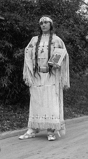 Ruth Muskrat, holding The Red Man In The United States (1919), by Gustavus Elmer Emmanuel Lindquist (1886-1967), on December 13, 1923. The book’s beaded cover and dress were made by an Indian woman of the Cheyenne tribe, Fish Woman. The book is an study of the social, religious, and economic life of American Indians, made under the auspices of the Institute of Social and Religious Research.