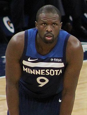 Deng bending forward in the Timberwolves' navy blue uniform