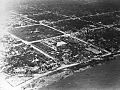 Aerial black and white image of a destroyed city along the coast. Almost all buildings are flattened.
