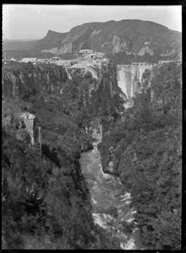 Black and white image of a dam under construction in a narrow ravine