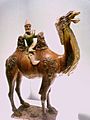 Ceramic statue of a small amn riding a large camel