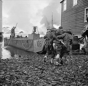 Wounded being helped onto a landing craft