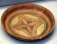 Handmade pottery shallow plate. The interior is decorated with a floral design in the center, with polychrome in black and red on the buff surfaces. From Tell Arpachiyah, Iraq. Halaf period, 6000-5000 BCE