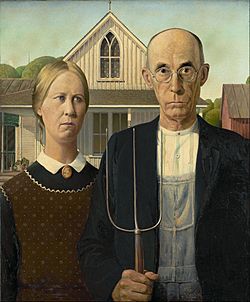 Man and woman with stern expession stand side-by-side. The man holds a pitch fork.
