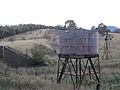 Derelict windpump with water tank in the foreground next to the Boorowa railway in Galong NSW Australia