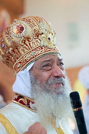 H.H. Pope Shenouda III smiling while giving a word