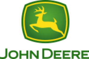 A green, rounded square with a yellow jagged outlines on the four sides of the square near the outside of its green border can be seen. In the middle of the yellow outline, a biological entity drawn outlined in yellow can be seen in a leaping position. This animal is commonly referred to as a deer. Underneath the deer and the green box, the words in caps lock, 'JOHN DEERE' can be read.