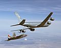 Rear/starboard view of aerial refueling tanker transferring fuel to a jet fighter via a long boom. The two aircraft are slightly banking left.