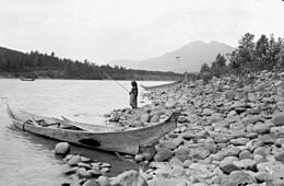 Girl fishing in the Skeena River beside a dugout cedar canoe, Kitwanga (Gitwangak-Gitwangax) (41994622490)