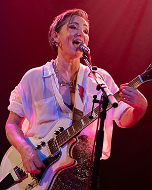 A photograph of Tunstall smiling, looking away from the camera. A microphone is positioned in front of her face.