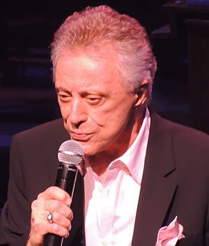 Valli singing into a microphone onstage