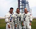 Fred Haise (left) Jim Lovell, and Ken Mattingly pose in front of the launch pad