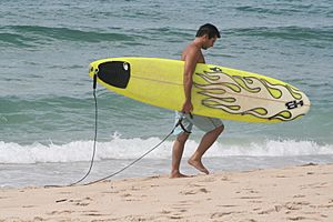 Sufer carrying surfboard along the beach