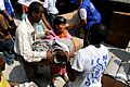 US Navy 100224-N-6278K-173 International Organization for Migration volunteers pass out shelter packages for earthquake survivors, in Port-au-Prince, Haiti