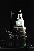 The clock tower of a large brick building at night