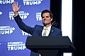 Gaetz waving in front of a lectern. "Students for Trump" logo emblazon the background.