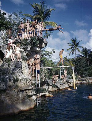 Kids diving off rock hill at the Venetian Pool tourist attraction in Coral Gables, Florida