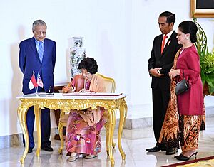 Siti Hasmah Mohamad Ali signing document witnessed by Mahathir Mohamad and Joko Widodo