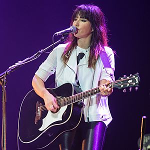 A photograph of Tunstall smiling, looking away from the camera. A microphone is positioned in front of her face.