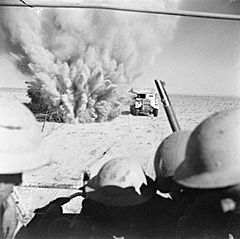 A mine explodes close to a British truck as it carries infantry through enemy minefields and wire to the new front lines