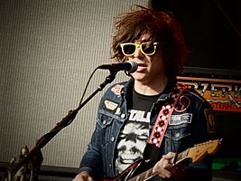 A man with yellow sunglasses singing and playing guitar