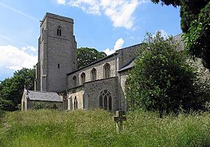A stone church seen from the southeast with a chancel, nave with clerestory, south aisle and porch and a tower