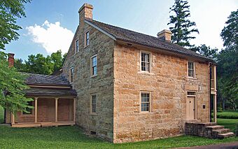 Two-and-a-half-story stone house with a small one-story addition