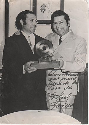 Scanned black and white image of two men holding an award. Image appears to be signed by Farina with a note in Spanish.