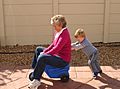 Child pushing grandmother on plastic tricycle
