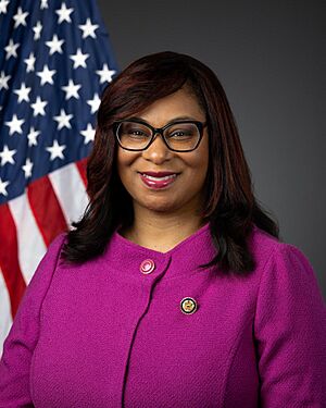 Bynum smiling in front of the U.S. flag, wearing her House member pin and a pink jacket.