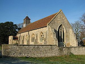 A stone church with a red tiled roof seen from the south-east. It has a south porch and a louvred belfry at the west end; there is no external division between the nave and the chancel