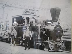 Men pose in front of an old steam engine.