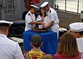 US Navy 090917-N-6692A-047 Lt. John Madea holds his daughter as she is baptized with holy water from the ship's bell of the amphibious dock landing ship USS Tortuga (LSD 46)