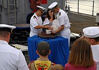 US Navy 090917-N-6692A-047 Lt. John Madea holds his daughter as she is baptized with holy water from the ship's bell of the amphibious dock landing ship USS Tortuga (LSD 46)