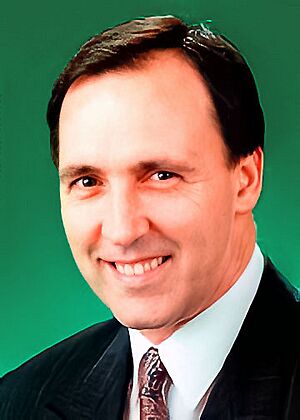 Keating smiling in front of a green background