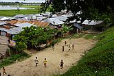 Children play football on a dirt pitch near tin-roofed houses on the bank of the Itaya River.