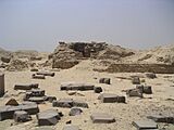 Scattered blocks of limestone and black basalt and a heap of rubble in the background.