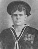 Head and shoulders of a young white man with thick hair wearing a flat cap and a sailor suit with three medals on the left breast.