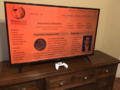 TCL TV set on stand on dresser, HDMI-connected to Windows computer, the blue light filter on, on WP homepage, with XB1 controller a remote input device Bluetooth-connected to the PC, which uses Controller Companion
