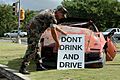 US Navy 051130-N-7293M-003 U.S. Navy Master-at-Arms 1st Class Robert C. Tempesta places a "Don't Drink and Drive" sign in front of a wrecked car outside the front gate of U.S. Naval Base Guam