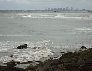 Lynn Massachusetts surfers riding waves with Boston in background