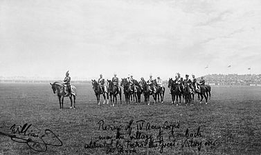 Old photograph showing men on horseback standing in a field.