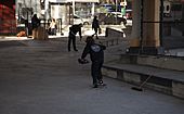A skateboarder pushes holding a dust bin at Golconda Skatepark