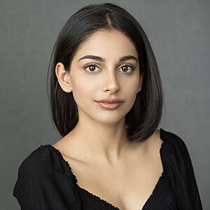 close-up of Banita Sandhu wearing a black, low-cut top, looking directly at camera with slight smile