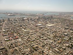 Aerial view of downtown Long Beach, California, looking southwest. San Pedro Bay and the Port of Long Beach are visible beyond, with Catalina Island faintly visible on the horizon.