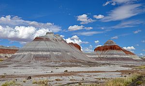 Conical rock formations showing horizontal banding in red, white, and shades of grey